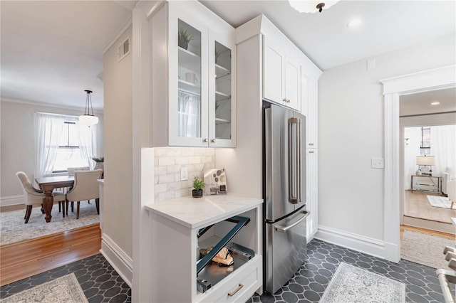 kitchen with dark hardwood / wood-style floors, decorative backsplash, high quality fridge, white cabinetry, and light stone counters