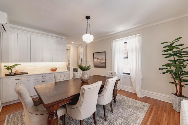 dining room featuring light hardwood / wood-style floors, ornamental molding, and a wall mounted AC