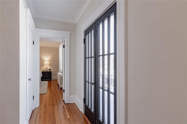 hallway with radiator heating unit, light wood-type flooring, french doors, and crown molding