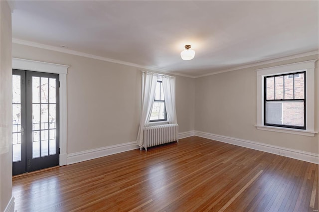 empty room with radiator, crown molding, and hardwood / wood-style flooring