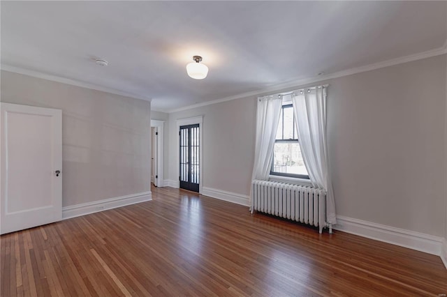 spare room with radiator, crown molding, and dark hardwood / wood-style floors