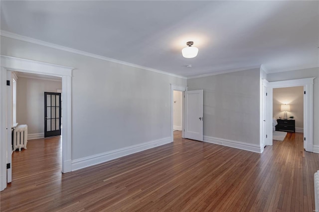 empty room featuring dark hardwood / wood-style floors, radiator, and ornamental molding