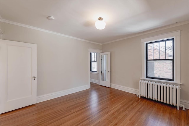 unfurnished room featuring crown molding, hardwood / wood-style floors, and radiator heating unit