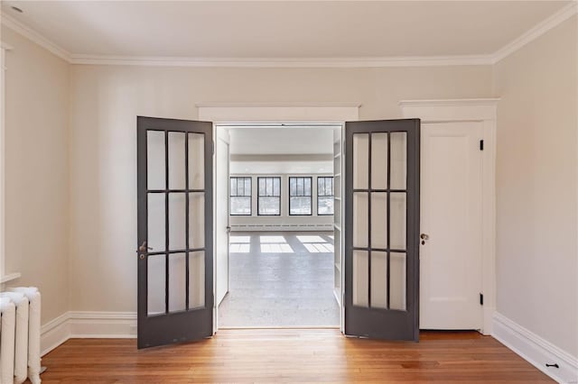 unfurnished room featuring crown molding, french doors, radiator heating unit, and a baseboard radiator