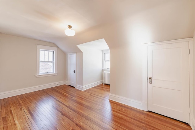 additional living space with radiator heating unit, lofted ceiling, and light wood-type flooring