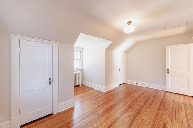 bonus room featuring light wood-type flooring, vaulted ceiling, and radiator heating unit