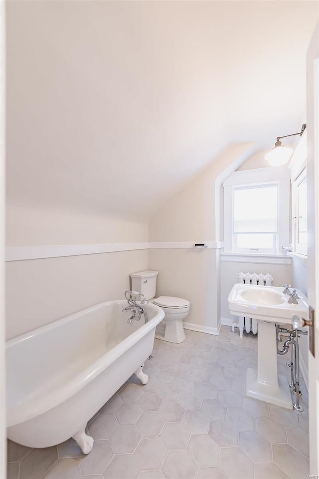 bathroom with toilet, tile patterned flooring, vaulted ceiling, and a washtub