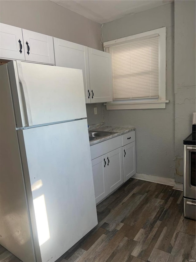 kitchen featuring dark wood-type flooring, sink, white refrigerator, and white cabinetry