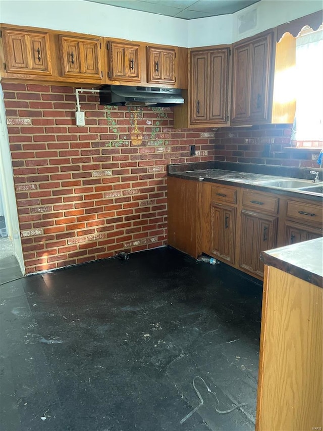 kitchen featuring brick wall and sink