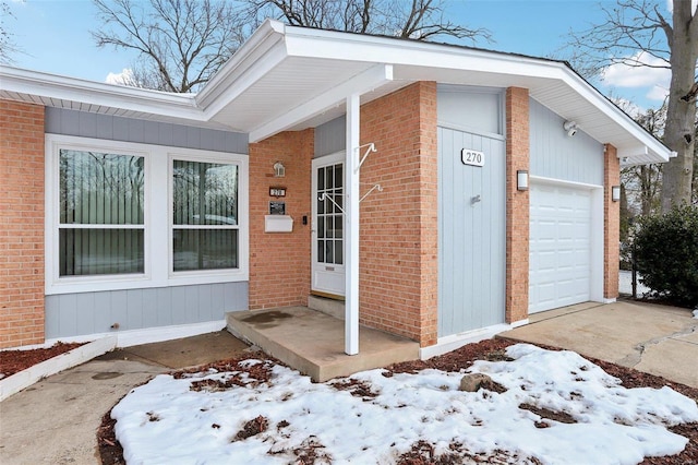 snow covered property entrance with a garage