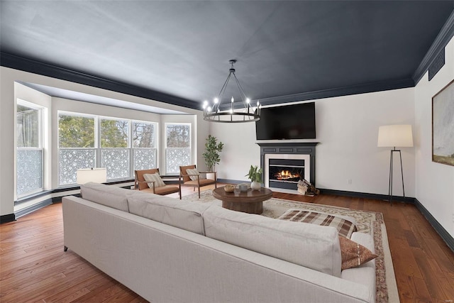 living room with crown molding, hardwood / wood-style floors, and a chandelier