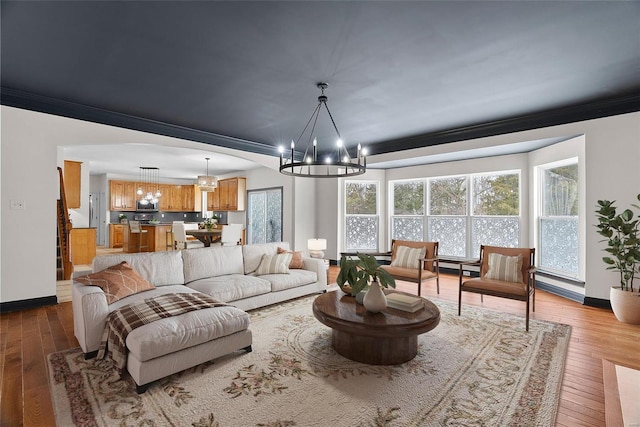 living room featuring hardwood / wood-style flooring, ornamental molding, and a chandelier