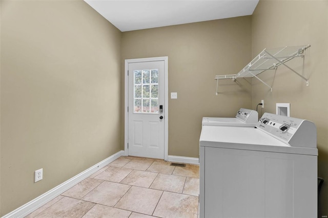 washroom with light tile patterned floors, baseboards, washing machine and dryer, and laundry area