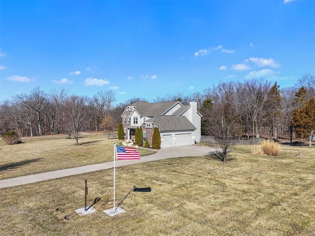 view of front of house featuring a garage, driveway, a chimney, and a front yard