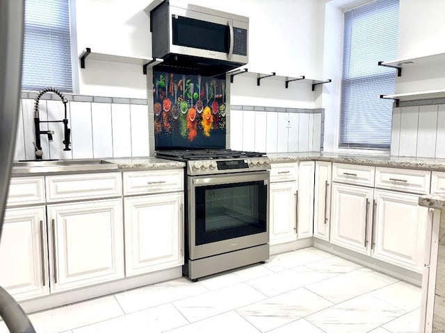 kitchen with sink, stainless steel appliances, white cabinets, and light stone countertops