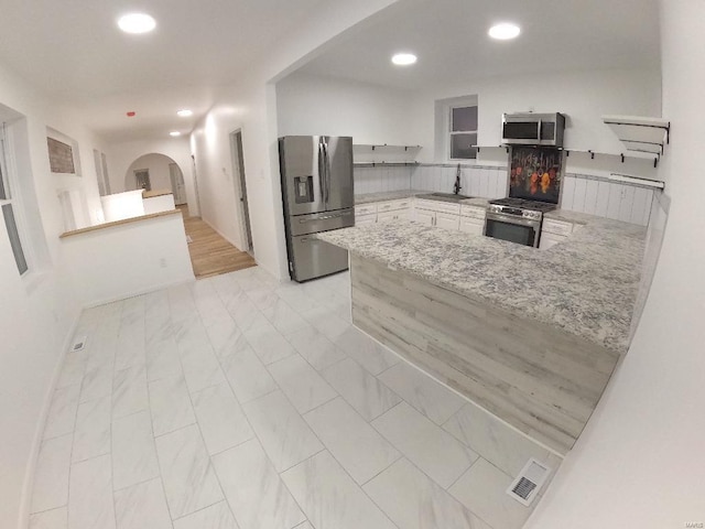 kitchen featuring white cabinetry, appliances with stainless steel finishes, kitchen peninsula, and sink