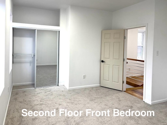 unfurnished bedroom featuring light colored carpet and a closet