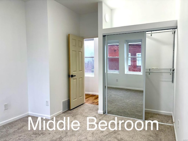 unfurnished bedroom featuring light colored carpet and a closet