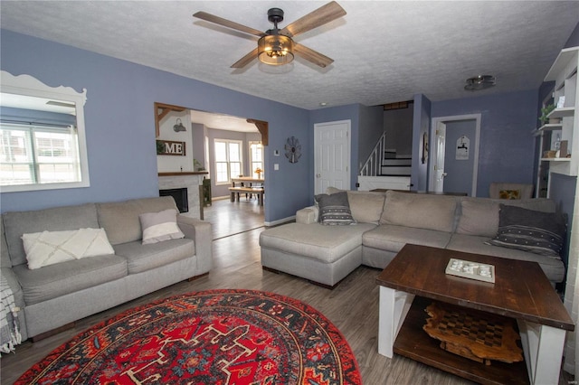 living room with ceiling fan, light hardwood / wood-style flooring, and a textured ceiling