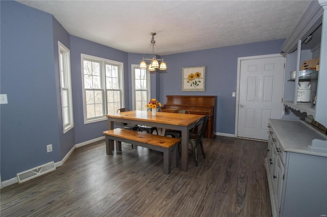 dining room with dark hardwood / wood-style floors, a textured ceiling, and a notable chandelier