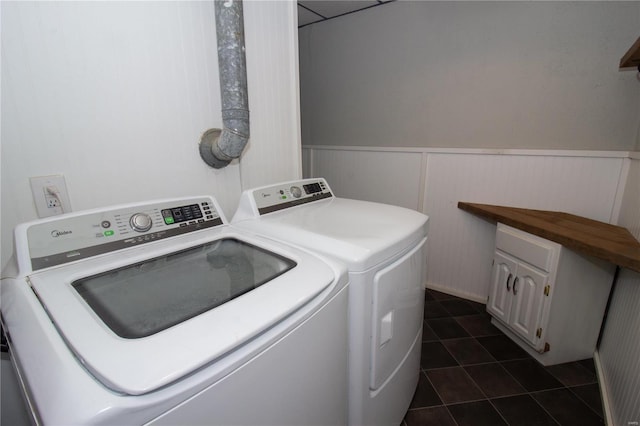 clothes washing area with cabinets, washer and dryer, and dark tile patterned flooring