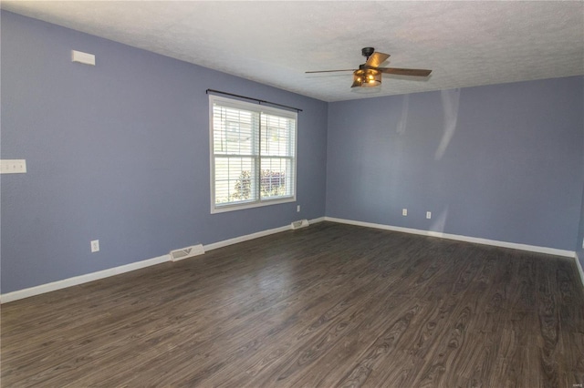 spare room with baseboards, a textured ceiling, a ceiling fan, visible vents, and dark wood finished floors