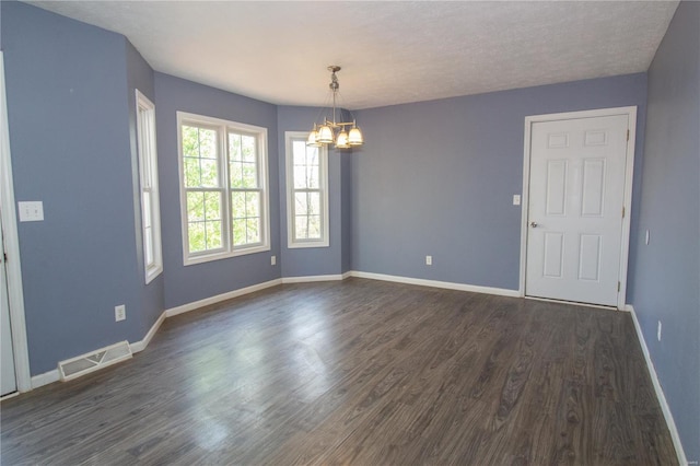 unfurnished room with dark wood-style flooring, visible vents, baseboards, and a notable chandelier
