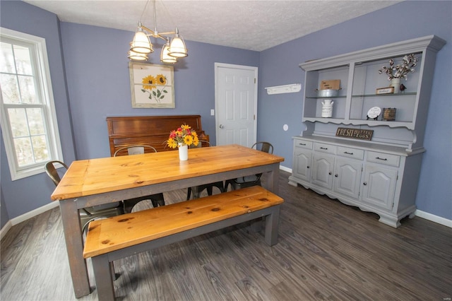 dining area with dark wood-style flooring, baseboards, a chandelier, and a textured ceiling