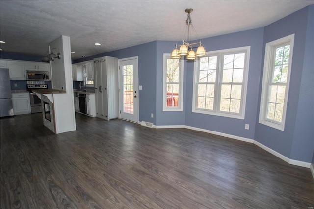 unfurnished living room with a chandelier, dark wood-type flooring, and baseboards