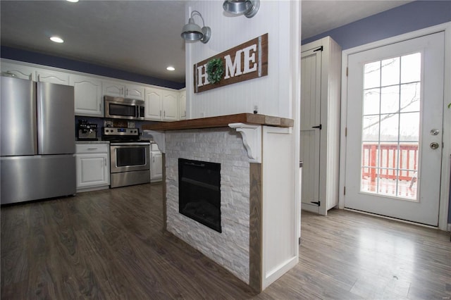 kitchen with recessed lighting, a fireplace, white cabinets, dark wood finished floors, and stainless steel appliances