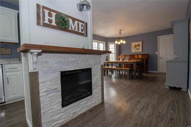 living area featuring an inviting chandelier, dark wood finished floors, and a stone fireplace