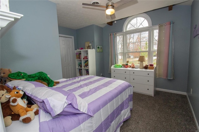 bedroom with a closet, baseboards, dark carpet, a ceiling fan, and vaulted ceiling