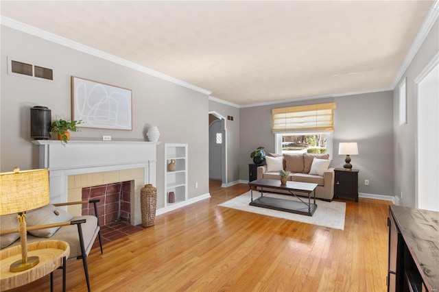 living room with crown molding, light hardwood / wood-style flooring, and a tile fireplace