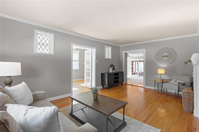 living room featuring crown molding, plenty of natural light, and light hardwood / wood-style flooring