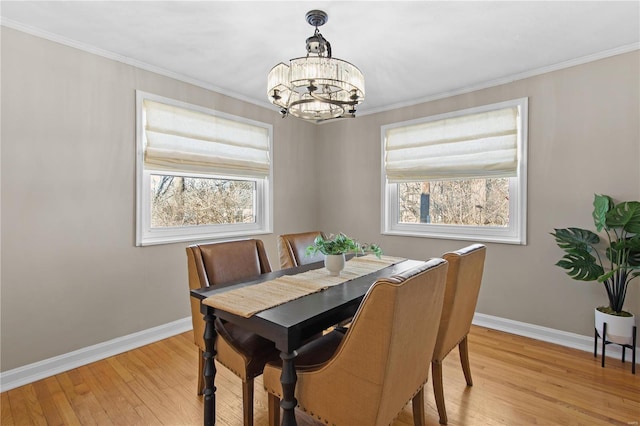 dining space with crown molding, an inviting chandelier, and light hardwood / wood-style floors