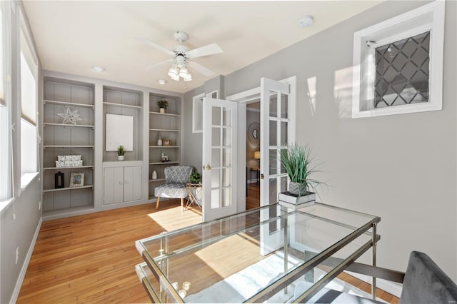 office area featuring french doors, ceiling fan, hardwood / wood-style floors, and built in features