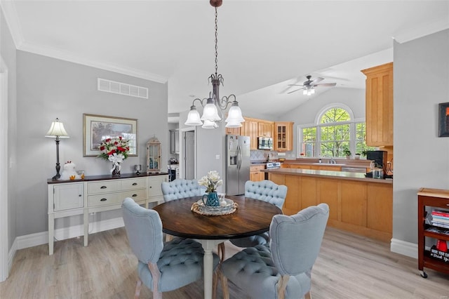 dining space with light wood-type flooring, ceiling fan, vaulted ceiling, and sink