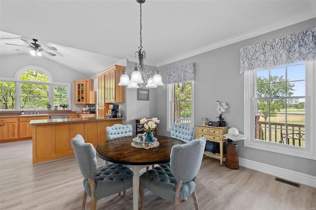 dining space with ceiling fan with notable chandelier, sink, vaulted ceiling, light hardwood / wood-style flooring, and crown molding