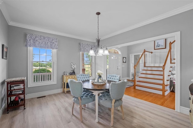 dining area with a chandelier, ornamental molding, and light hardwood / wood-style floors