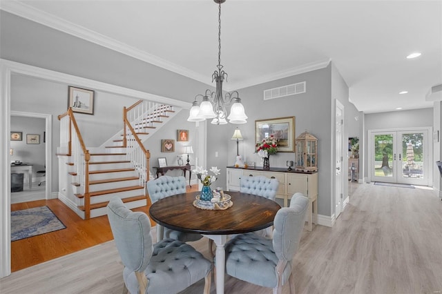 dining area featuring light wood-type flooring, a notable chandelier, french doors, and crown molding