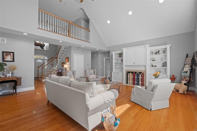 living room featuring high vaulted ceiling, a fireplace, and light hardwood / wood-style floors