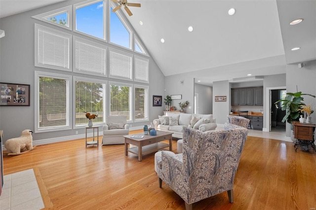 living room with high vaulted ceiling, ceiling fan, and light wood-type flooring