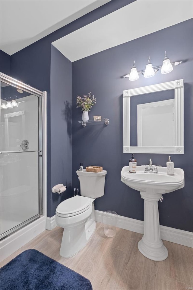 bathroom featuring a shower with shower door, toilet, and hardwood / wood-style flooring