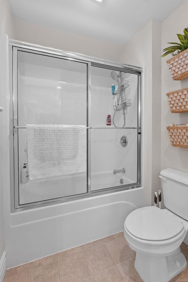 bathroom featuring toilet, tile patterned floors, and enclosed tub / shower combo