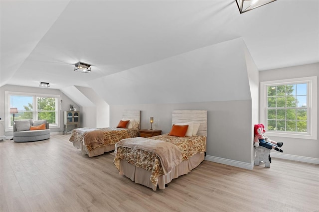 bedroom with vaulted ceiling, multiple windows, and light hardwood / wood-style flooring