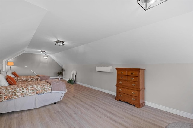 bedroom featuring a wall mounted AC, vaulted ceiling, and light hardwood / wood-style floors