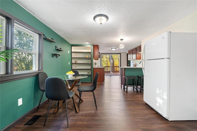 dining room with dark wood-type flooring and a textured ceiling