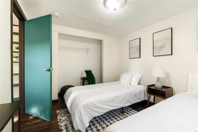 bedroom with a closet, dark hardwood / wood-style flooring, and a textured ceiling