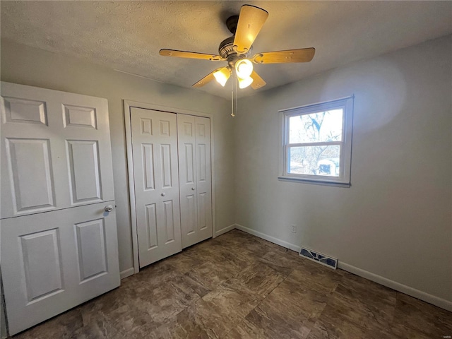 unfurnished bedroom featuring ceiling fan, a textured ceiling, and a closet