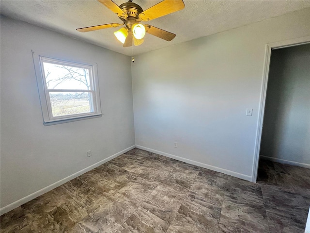 unfurnished room with ceiling fan and a textured ceiling